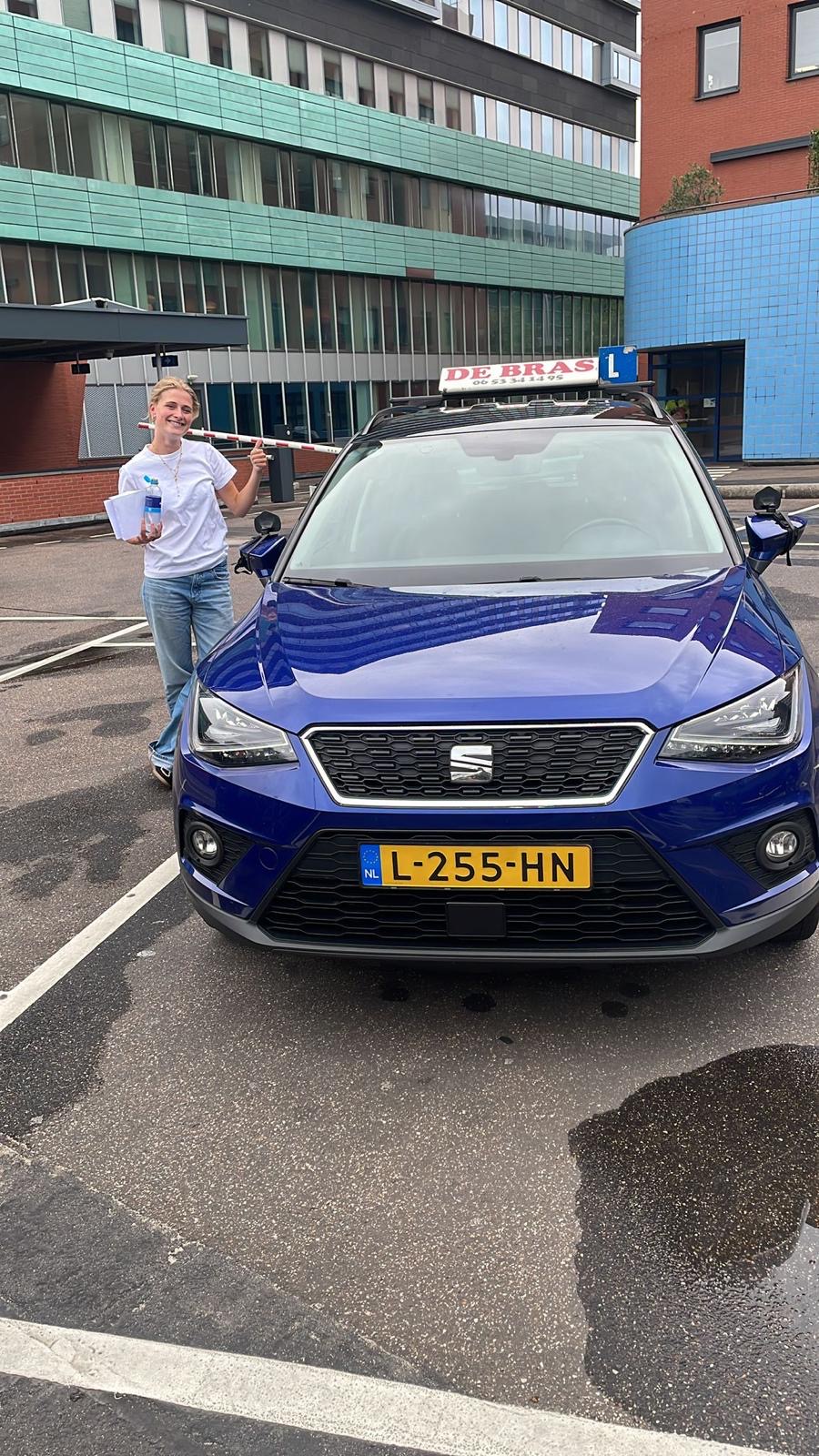 Geslaagde leerling van Rijschool De Bras bij de lesauto